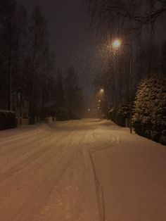 a snow covered street at night with the lights on