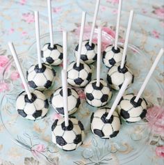 there are many soccer balls on the plate with toothpicks in them and one is black and white