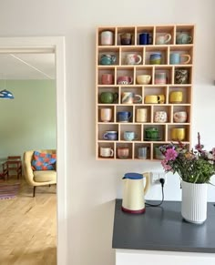 there is a vase with flowers in it on the counter next to a coffee pot