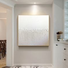 a large white painting hanging on the wall in a room with wooden chairs and tables