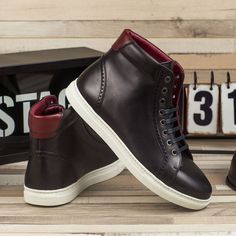 a pair of black and red shoes sitting on top of a wooden bench next to a sign