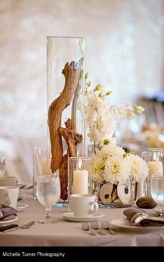 a centerpiece with flowers and candles is displayed on a table in front of other place settings