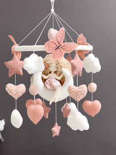 a pink and white baby mobile with hearts, stars and a teddy bear in the center