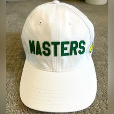 a white hat with the word masters on it sitting on carpeted floor next to coffee mug