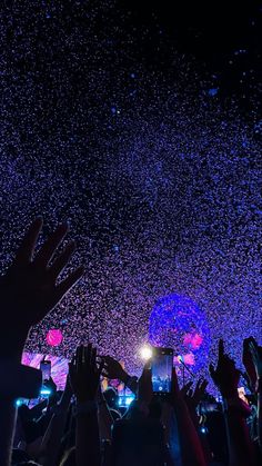 people are holding their hands up in the air as they watch fireworks and confetti