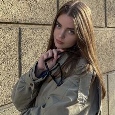 a beautiful young woman leaning against a brick wall