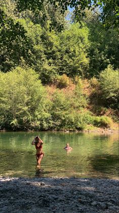 two people are wading in the water near some trees