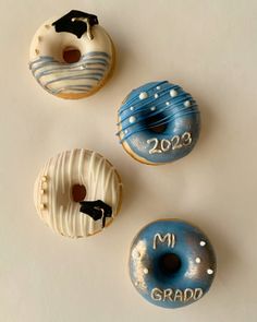 three doughnuts with frosting and graduation decorations on the top one is blue