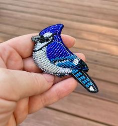 a hand holding a beaded blue bird brooch