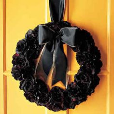 a black wreath hanging on a yellow door