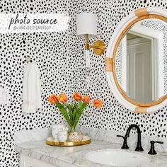 a bathroom with black and white wallpaper, gold faucet, marble counter top