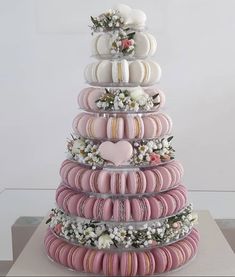 a large stack of doughnuts with flowers and hearts on each tier, all stacked high