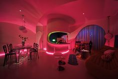 a living room filled with lots of furniture and pink lighting on the walls, along with round windows