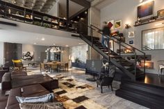 a living room filled with lots of furniture and a staircase leading up to the top floor