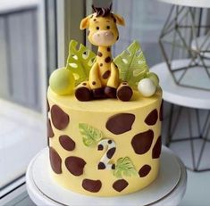 a cake decorated with a giraffe on top of a white table next to a window