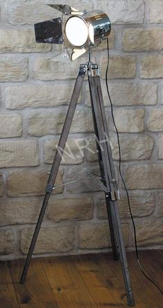 a tripod light on a wooden floor in front of a brick wall