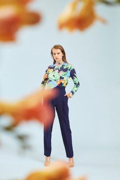 a woman is standing in front of some flowers