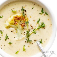 a white bowl filled with soup and garnished with herbs