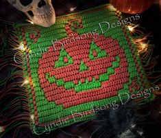 a crocheted pumpkin placemat on a table next to a skull and other halloween decorations