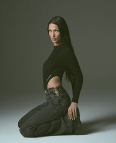 a woman in black shirt and jeans sitting on the ground