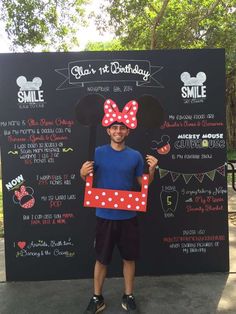 a man holding up a sign with minnie mouse on it