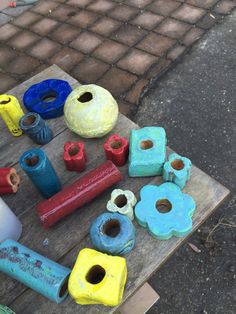 several different colored vases sitting on top of a wooden table next to each other