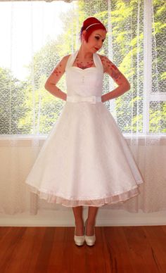 a woman standing in front of a window wearing a white dress and red headband