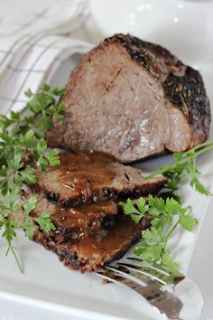 some meat is sitting on a plate with parsley next to it and a fork