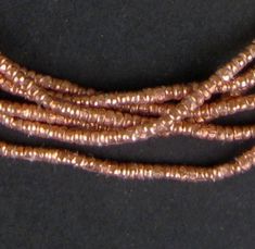 three strands of copper colored beads on a black background