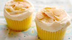 two yellow cupcakes with frosting on a table