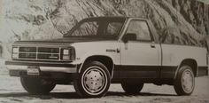 an old black and white photo of a truck parked in front of a mountain side