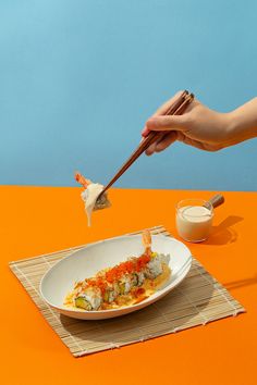 a person is holding chopsticks over a plate with food on it and dipping sauce