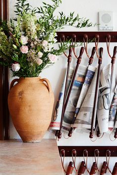 a vase filled with flowers sitting on top of a wooden shelf next to a wall