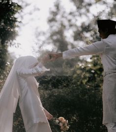 two people dressed in white are holding hands