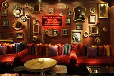 a living room filled with red couches and lots of framed pictures on the wall