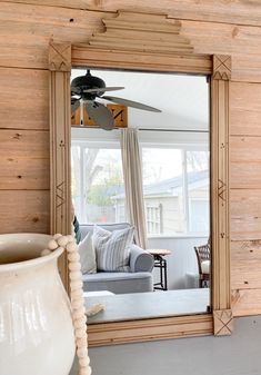 a living room with a large mirror on the wall and a white vase sitting next to it