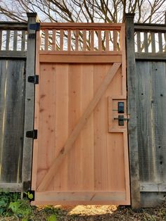 an open wooden gate in front of a fence