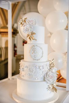 a wedding cake with white flowers and balloons