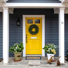 a yellow front door with two potted plants