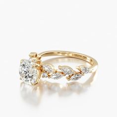 a yellow gold engagement ring with two pear shaped diamonds on the side and leaves around it