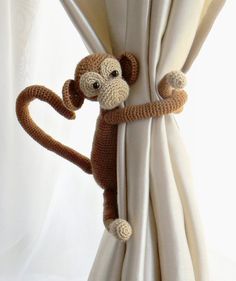 a stuffed monkey hanging from the side of a curtain