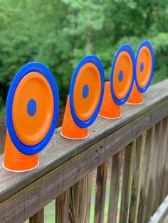 four orange and blue frisbees sitting on top of a wooden fence line