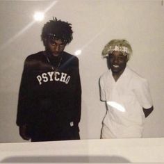 two young men standing next to each other in front of a white wall with the word psych on it