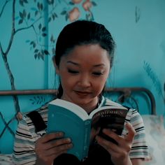 a woman sitting on a bed reading a book