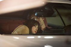 a man and woman sitting in the back seat of a car