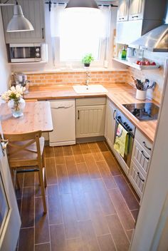 a small kitchen with wood floors and white cabinets is seen from the doorway to the dining room