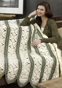 a woman sitting on a couch with a crocheted blanket