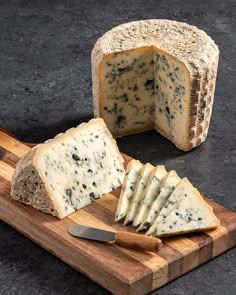 a piece of cheese on a cutting board next to a slice of bread with a knife