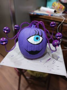 a purple pumpkin with an evil eyeball on it's head and eyes painted on the inside