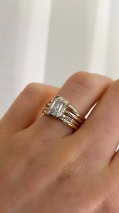 a woman's hand with two rings on it and an engagement ring in the middle